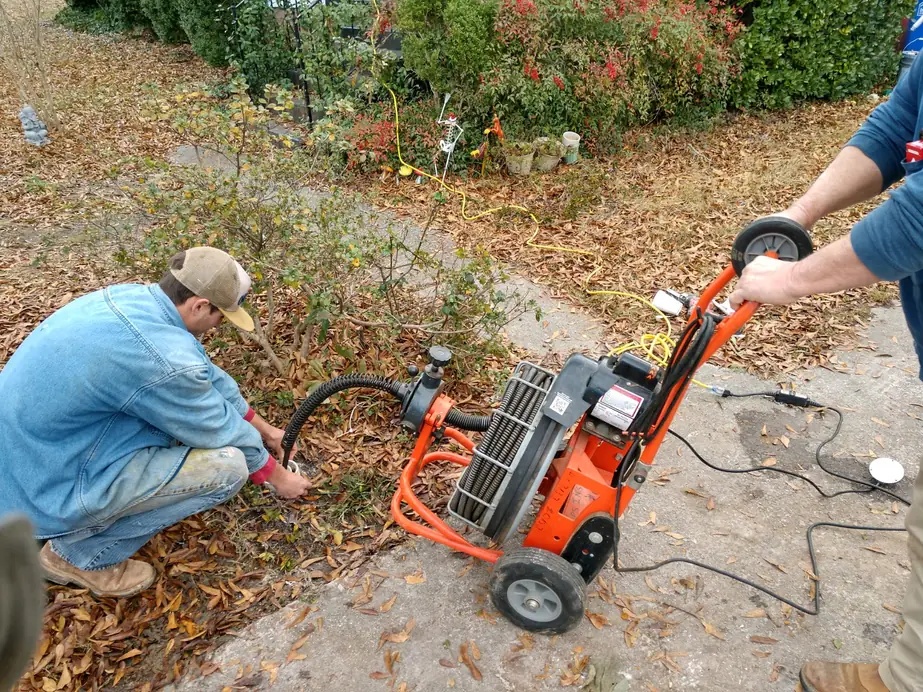 Two Fortune Plumbing technicians running a drain cleaning machine at a home